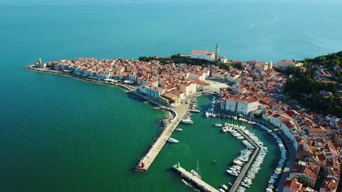 4K. Flight over old city Piran in the morning, aerial panoramic view with Tartini Square, St. George's Parish Church, marina and old houses. 
