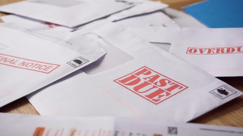 Debt Letters Piling Up with Bills Overdue, Past Due and Final Notice. Red Writing to Represent Economic Struggle, Unemployment, Home Repossession and Recession,