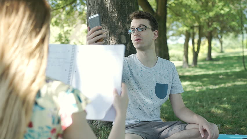 Boy having a videocall on smartphone while his friend is studying, steadycam shot
