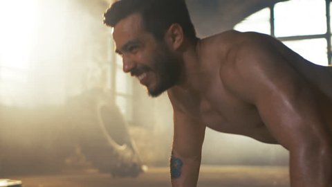 Muscular Shirtless Man Covered in Sweat Does Push-ups in a Deserted Factory Remodeled into Gym. Part of His Cross Fitness Workout/ High-Intensity Interval Training