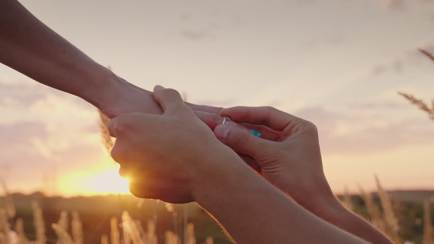 A man is dressing a woman for an engagement ring at sunset. In the frame are visible only hands | Shutterstock HD Video #29875693
