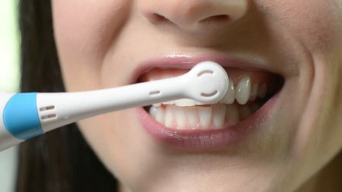 Close Up Of Woman Brushing Teeth With Electric Toothbrush