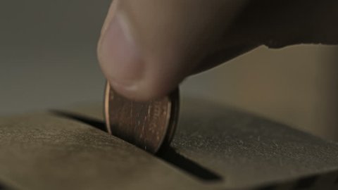 Coin being inserted into a vintage donation box
