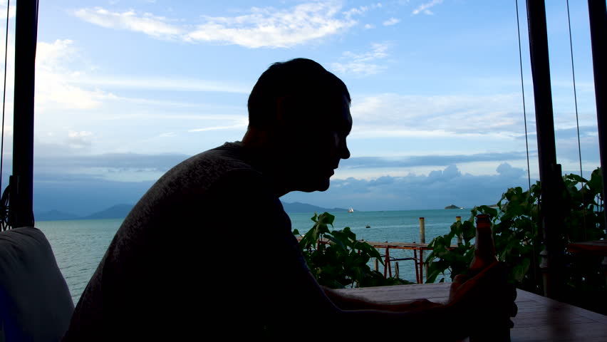 Silhouette of Sad Man Drinking Beer with Sea View
