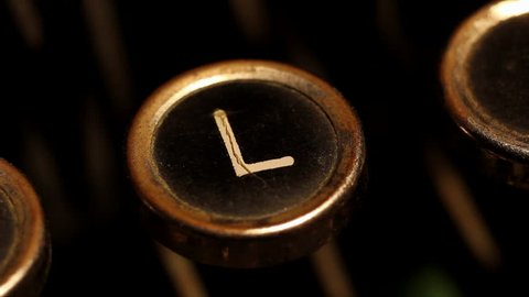 A male finger presses the letter "L" key on an old typewriter.