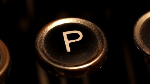 A male finger presses the letter "P" key on an old typewriter.