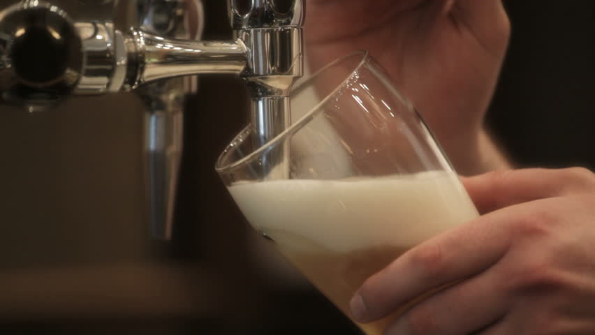Bar tender pours pint of bitter in pub.