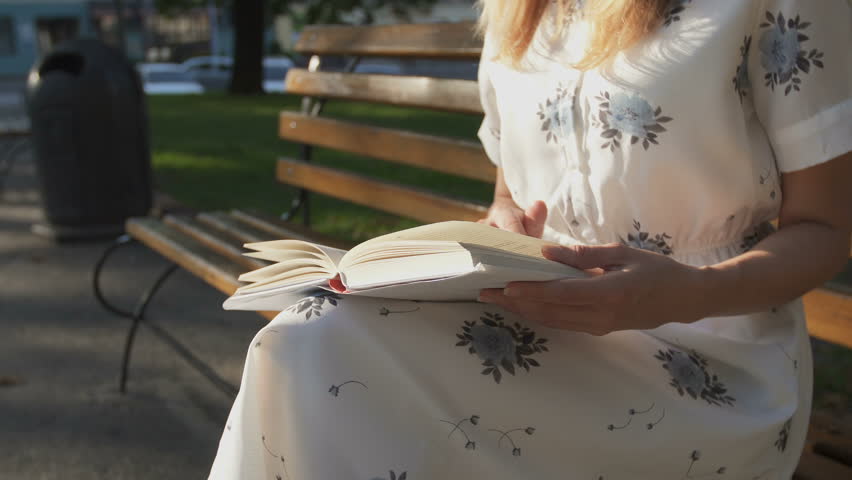 Romantic girl reading a book in the park in sunrise