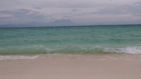 Video footage of a beautiful white sandy beach with turquoise color ocean