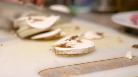 Chopping mushrooms with knife on chopping board