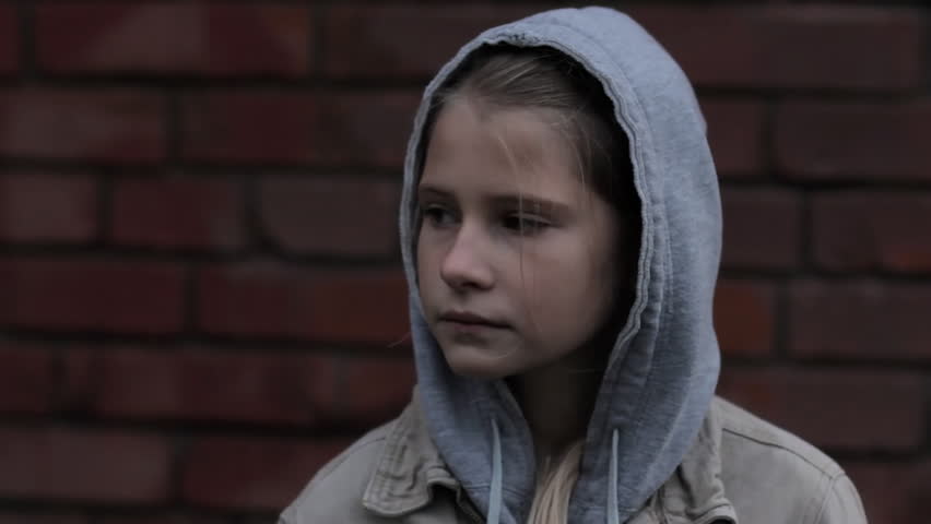 Refugee homeless child. Dark portrait of preteen girl standing in front of brick wall, she is looking unhappy and sad. | Shutterstock HD Video #29922187