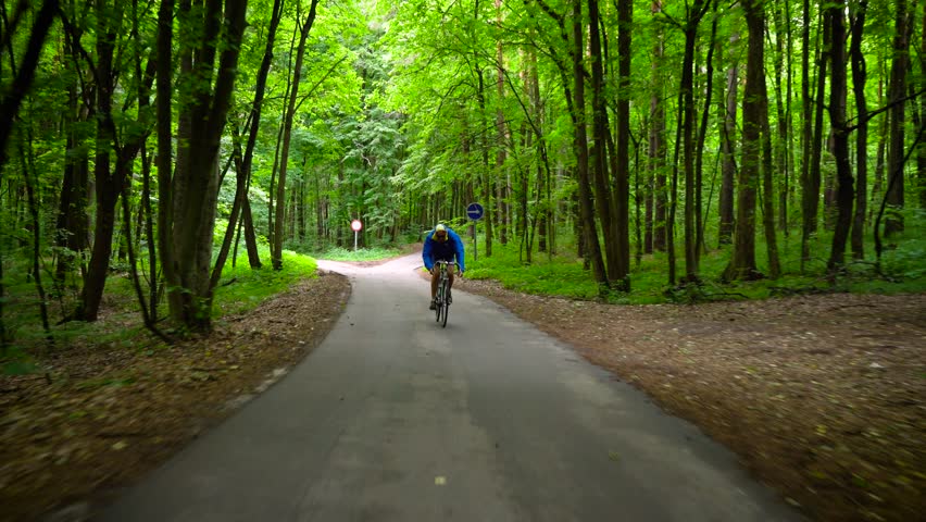 Middle-aged man is riding a road bike along a forest road | Shutterstock HD Video #29922574
