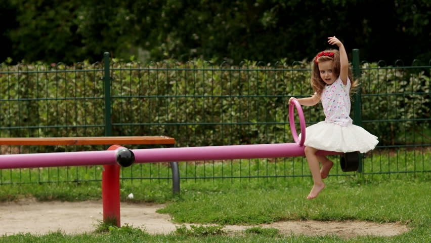 Outdoors Portrait of Cute Girl with Long Hair and Wreath of Red Flowers on the Playground During Summer Warm Day.