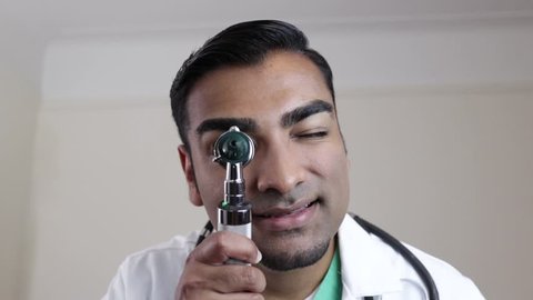 Doctor looking straight ahead through otoscope 