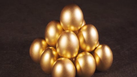 Rotating of golden eggs on black background, closeup shot