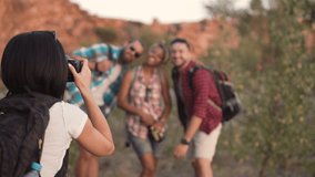 Anonymous woman taking shot of three friends posing with backpacks while traveling together. - Powered by Shutterstock - Get 15% off with code: PIKWIZARD15