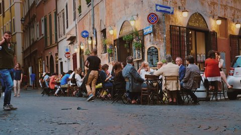 Rome, Italy - June, 2017: Street life in the center of Rome. Visitors eat in a cafe, walk along the street and take pictures of tourists