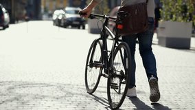 Close up on adult man with bicycle promenading outdoors