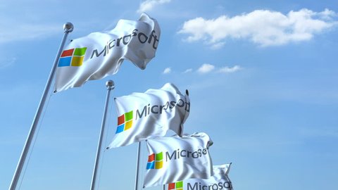 Waving flags with Microsoft logo against sky, seamless loop. 4K editorial animation