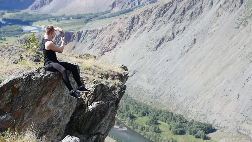 Strong man hiker taking photo with smart phone at mountain peak. Marvelous daybreak.