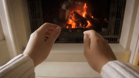 Slow motion video of female hands warming by the fireplace at chalet