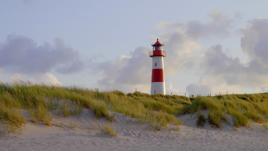 red an white lighthouse on top of an s sand dunes in beautiful sunset light on the german holiday island sylt  Royalty-Free Stock Footage #29947873