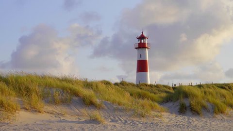 red an white lighthouse on top of an s sand dunes in beautiful sunset light on the german holiday island sylt 