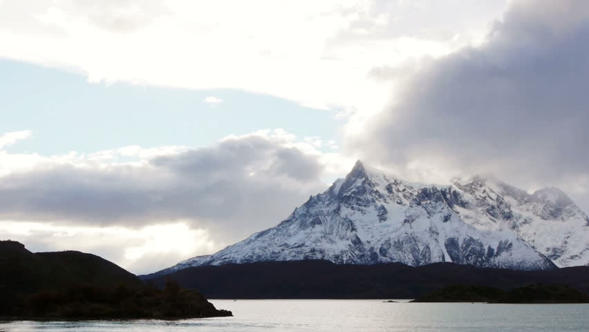 Pan across lake at base of mountains in Torres del Paine national park