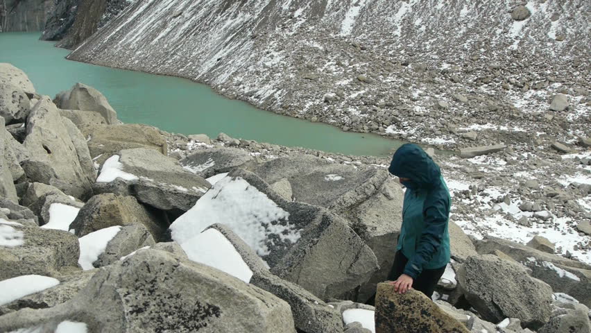 Woman climbs over boulders as camera reveals stunning view of Torres del Paine