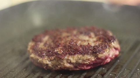 Cooking process of a Red meat unhealthy traditional hamburger made of 100% organic meat, on a sizzling frying pan used for home cook  