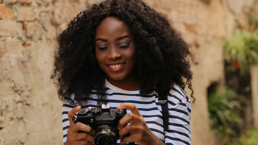 Young attractive woman taking photo by camera while traveling in the beatiful ancient city. Portrait shot.