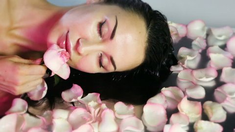 Woman with clean Healthy skin. Fresh Rose petals and pink rosebud. Natural Rose water for toning and skin cleaning. Beautiful Girl face. Natural Beauty and skincare. Rose Cosmetics. Spa Aromatherapy