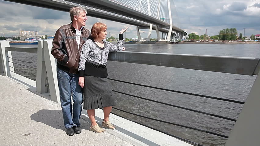 Elderly husband and wife are considering something in the distance on the Neva River at the Cable Bridge, St. Petersburg