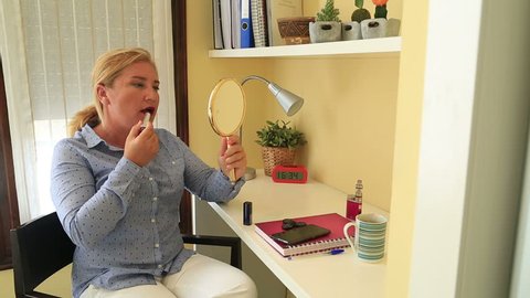 Businesswoman applying lipstick in office