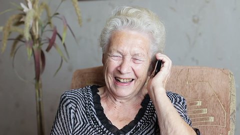 Cheerful old woman talking on the phone. She laughs and rejoices