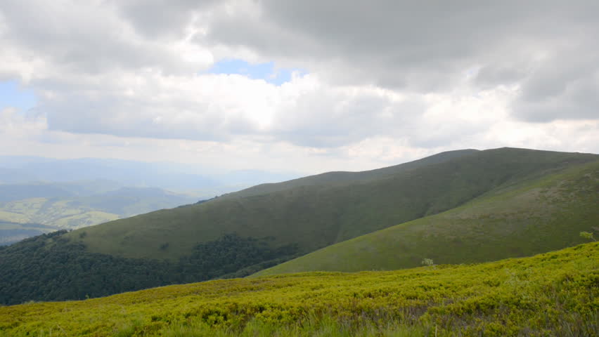 Father carries his son on his shoulders and walks on top of the mountain in the summer.