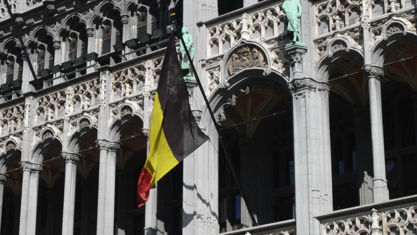 The Belgian flag waving at the Broodhuis facade at the famous Grand Place in downtown Brussels, Belgium.