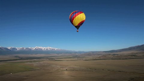 Hot Air Balloon flying across the sky in mountain landscape, Altai, Siberia. Landscape panorama. Aerial view.