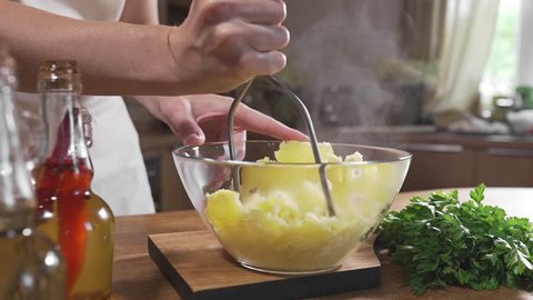 Chef mashes potatoes in a glass bowl, cooking food in the kitchen, boiled vegetables, vegetarian meal, healthy food