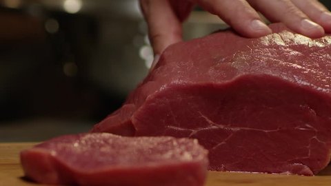 The chef cuts raw meat with the knife in Slow Motion 