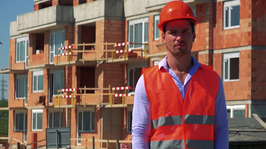 Construction worker points to the camera and agrees in front of building site Royalty-Free Stock Footage #29988472