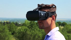 Young handsome man uses virtual reality glasses - countryside in the background - closeup of head 