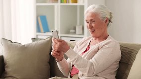technology, communication and people concept - happy senior woman with smartphone having video conference at home