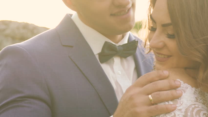 Tender wedding couple embracing and caressing in the golden sun rays outdoors