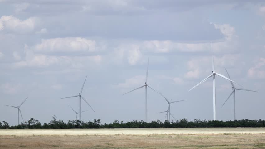 Wind turbines in the meadow produce alternative energy against the background of the sky