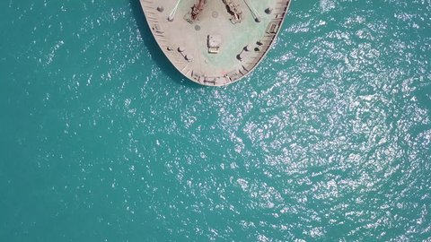 Large bulk carrier ship sailing / docking in open ocean - 4k top down aerial shot