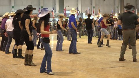 Cremona, Italy, May 2017 -  People dancing country line dance at a folk event, cowboy USA style. Men and women having fun choreography American horse festival. Music tradition jeans boots and flag