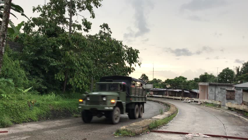 Marawi, Philippines - July 17, 2017: Military truck and ambulances going by on paved road in Marawi, Philippines