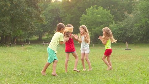 Happy group of little friends playing and clapping together outdoors in the summer. Slow motion