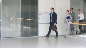 Group of business people walking confidently along the office corridor with a young leader at the head